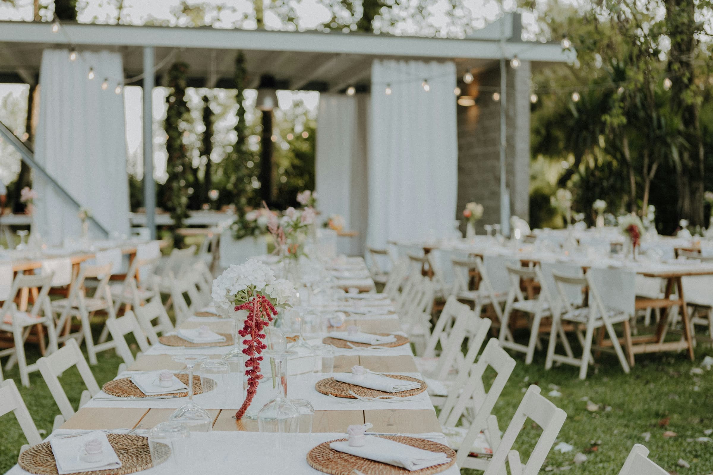 Banquete de boda al aire libre con mesas vestidas, flores y luces cálidas