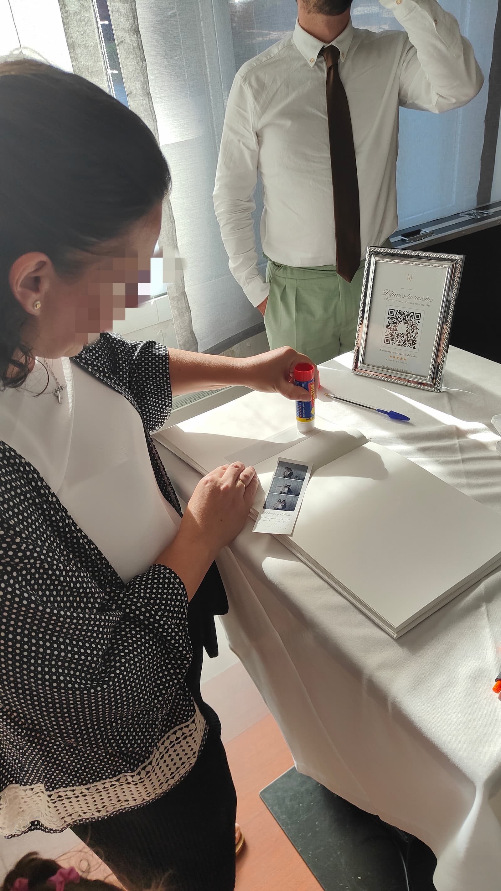 Una invitada pegando su tira de fotos en el álbum