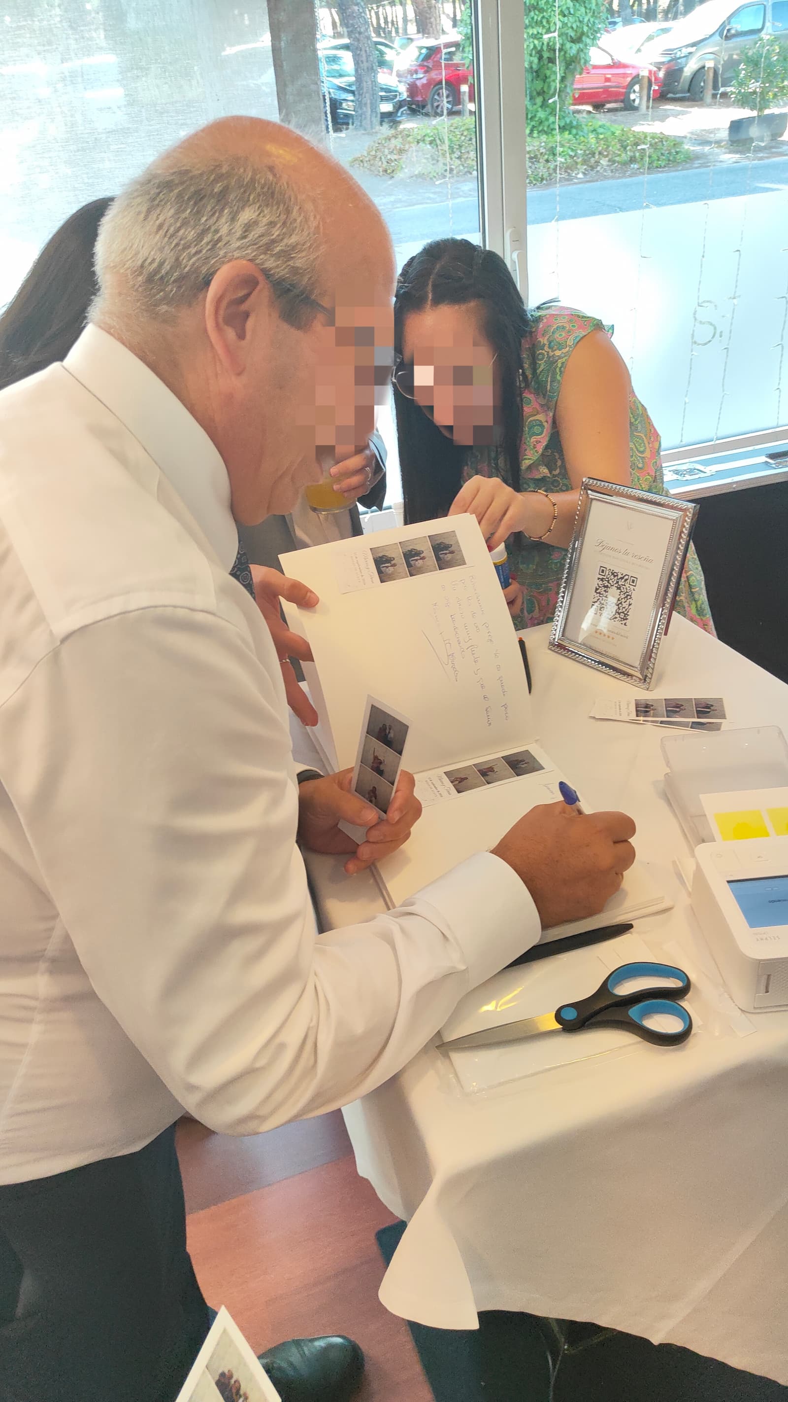 Un invitado escribiendo su dedicatoria junto a su tira de fotos